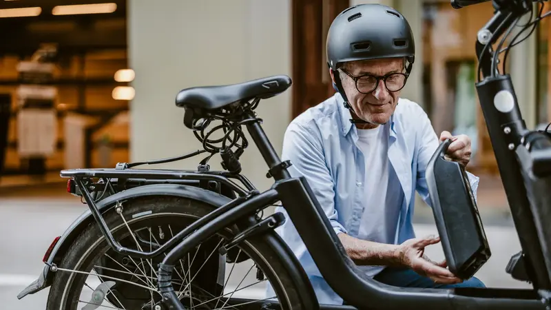 Älterer Radfahrer mit Helm, bereitet sein E-Bike vor.